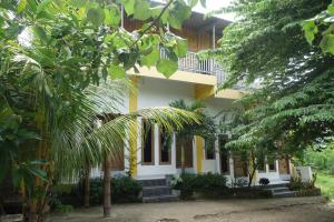a yellow and white building with trees in front of it at Tarsan Homestay in Labuan Bajo