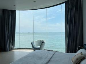 a bedroom with a large window with a chair and the ocean at Nancy Sweet Condotel Vung Tau 1 in Vung Tau
