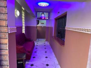 Cette chambre violette dispose d'un canapé et d'une télévision. dans l'établissement Crest Suite and Lifestyle, à Owerri