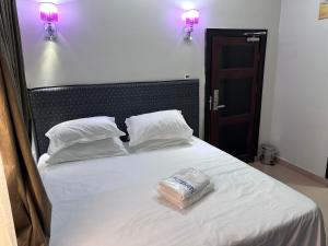 a bed with two pillows and a bag on it at Crest Suite and Lifestyle in Owerri