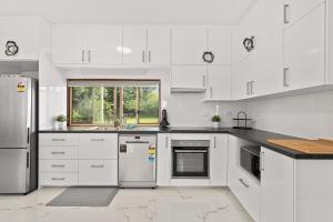 a white kitchen with white appliances and a window at Moana Ocean - C21 SouthCoast Holidays in Moana