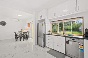 a kitchen with white cabinets and a dining room with a table at Moana Ocean - C21 SouthCoast Holidays in Moana
