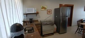 a kitchen with a stove and a refrigerator at Hospedagem Sol Nascente - Pé na Areia in Arroio do Silva