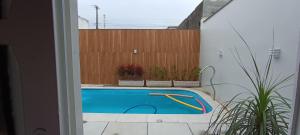 - une piscine dans un jardin avec une clôture en bois dans l'établissement Hospedagem Sol Nascente - Pé na Areia, à Arroio do Silva
