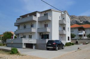 een zwarte auto geparkeerd voor een wit gebouw bij Apartment Leo in Baška