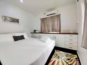 a white bedroom with two beds and a window at Guesthouse in Suva in Suva