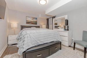 a white bedroom with a bed and a chair at Luxury Basement Apartment in Oakville in Oakville