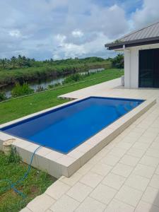 a blue swimming pool in a yard with a house at Large 4 bedroom villa with Pool in Sonaisali Nadi in Nadi