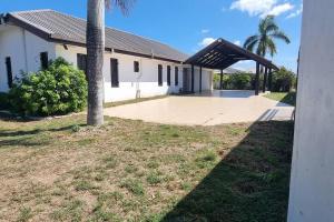 a large white building with a porch and a palm tree at Large 4 bedroom villa with Pool in Sonaisali Nadi in Nadi
