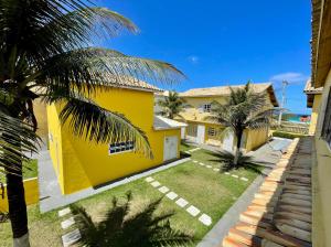 une maison jaune avec des palmiers devant elle dans l'établissement Duplex Miramar - Praia das Dunas - Pé na Areia, à Cabo Frio