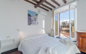 a white bedroom with a bed and a large window at Stunning Apartment In Recco With Outdoor Swimming Pool, 1 Bedrooms And Wifi in Recco