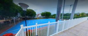 a pool with a white fence and a basketball court at Casa de descanso en Girardot in Girardot