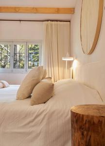 ein Schlafzimmer mit einem weißen Bett mit Kissen und einem Tisch in der Unterkunft Hestia At San Antonio De Areco I Estancia Paraso in San Antonio de Areco