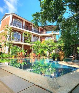 una piscina di fronte a un edificio di The Coconut House Hotel a Battambang