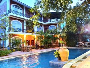 un hotel con piscina di fronte a un edificio di The Coconut House Hotel a Battambang