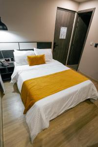 a bedroom with a large bed with a yellow blanket at Balmoral Plaza Hotel in Pereira