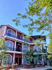 un edificio de ladrillo rojo con balcón y mesas en The Coconut House Hotel, en Battambang