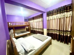 1 dormitorio con 2 literas y paredes moradas en Backpackers hostel and transient house, en Nangalisan