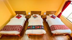 3 camas en una habitación con una pared amarilla en Andean Atoq Hostel, en Cusco
