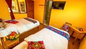1 dormitorio con 2 camas y mesa con lámpara en Andean Atoq Hostel, en Cusco