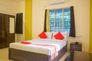 Un dormitorio con una cama con almohadas rojas y una ventana en Super Collection O D'Villa, en Pune