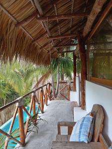 a porch of a resort with a straw roof at El Puente in El Paredón Buena Vista