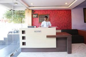 a man talking on a phone at a reception desk at OYO Hotel Kanha Palace in Kota