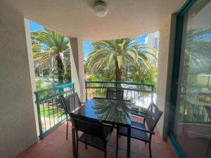 a table and chairs on a balcony with palm trees at CHA Private Apts Aruba Beach in Gold Coast