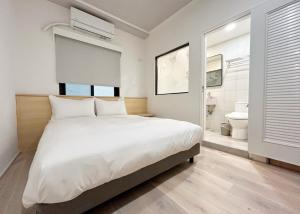 a bedroom with a large white bed and a bathroom at Yan Bin Hotel in Tainan