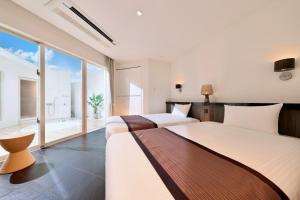 two beds in a room with a large window at Crystal Villa Miyakojima Sunayama Beach in Miyako Island +79 photos