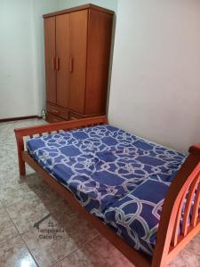 1 cama con edredón azul y armario de madera en Temporada em Cabo Frio, en Cabo Frío