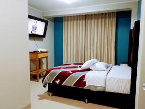 1 dormitorio con 1 cama y TV en la pared en HOSTAL TOSCANO SUITES, en El Tambo