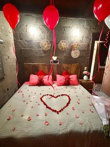 Una cama con un corazón hecho de rosas y globos en Moderna cabaña con Jacuzzi, en Huasca de Ocampo