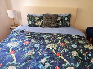 a bed with a blue comforter and pillows at Tranquil and cosy guest house in Oakleigh East