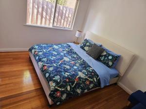 a bed with a blue comforter and pillows in a bedroom at Tranquil and cosy guest house in Oakleigh East