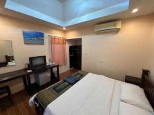 1 dormitorio con 1 cama y escritorio con TV en Bansuan Sangtawan Resort, en Uttaradit