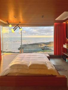 1 dormitorio con 1 cama grande y ventana grande en Hi Gimnyeonga, en Jeju