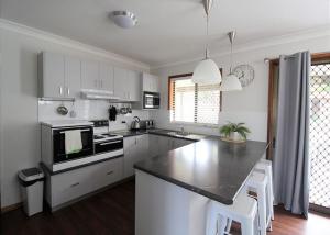 a kitchen with white cabinets and a black counter top at Breakaway, 11 Scott Street in Crescent Head