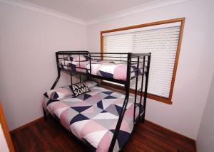 two bunk beds in a room with a window at Breakaway, 11 Scott Street in Crescent Head