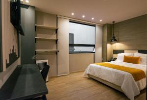 a bedroom with a bed and a desk and a window at Balmoral Plaza Hotel in Pereira