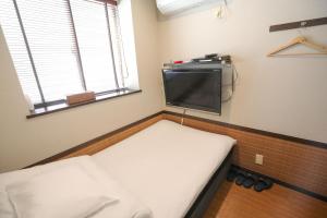 Habitación pequeña con 2 camas y TV de pantalla plana. en プチホテル　コスモス, en Tokio
