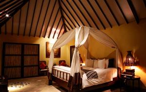 Hotel Tugu Lombok - CHSE Certified في تانجونغ: غرفة نوم بسرير مع مظلة