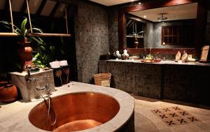 a bathroom with a wooden tub and a sink at Hotel Tugu Lombok - CHSE Certified in Tanjung