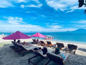 um grupo de pessoas sentadas em cadeiras em uma praia em Lushy Hostel Nusa Penida em Nusa Penida