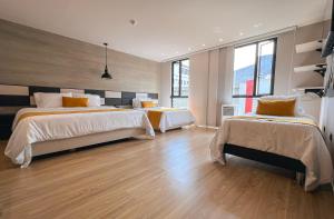 a bedroom with two beds and a wooden floor at Balmoral Plaza Hotel in Pereira