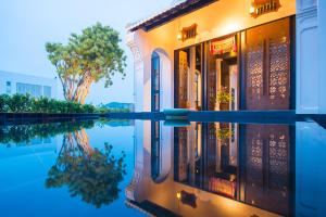 a building with its reflection in the water at Little Nyonya Hotel in Phuket Town