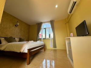 a bedroom with a bed and a tv and a window at Venice Hotel Hua Hin in Hua Hin