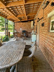 eine Außenterrasse mit einem Holztisch und Stühlen in der Unterkunft Hoeve Hulsbeek: genieten van de natuur en de rust in Geetbets
