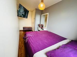 a bedroom with a bed with a purple blanket at Habitaciones privadas con vista al parque castilla in Lima
