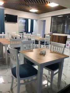 een eetkamer met houten tafels en witte stoelen bij Ibn Sino Hotel in Bukhara